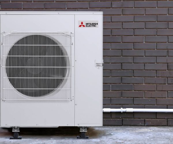 Air conditioner compressor install on concrete floor next to vintage dark brown brick wall behind the home office.